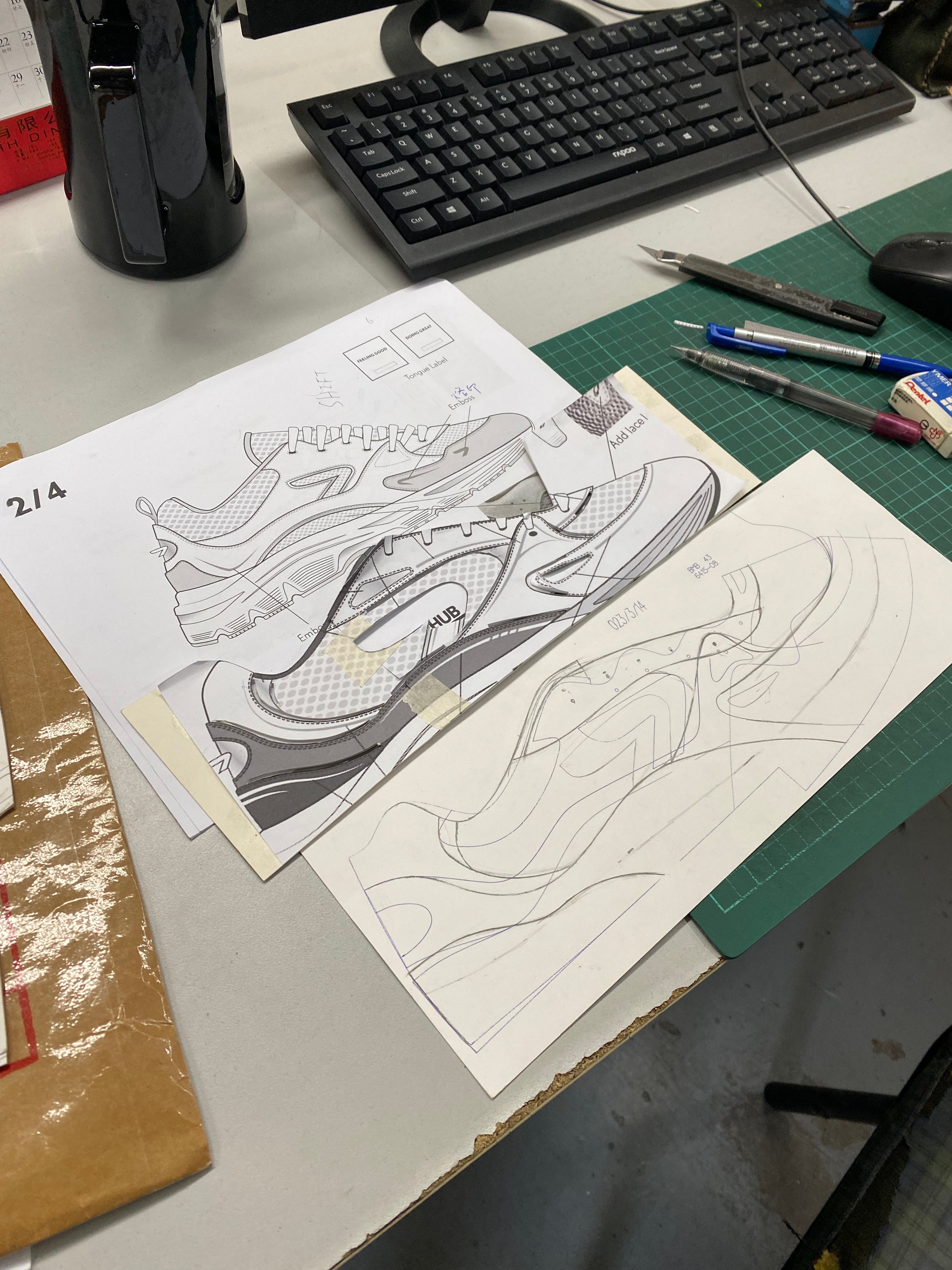 Design sketches of a sneaker on paper with a keyboard and stationery items in the background.