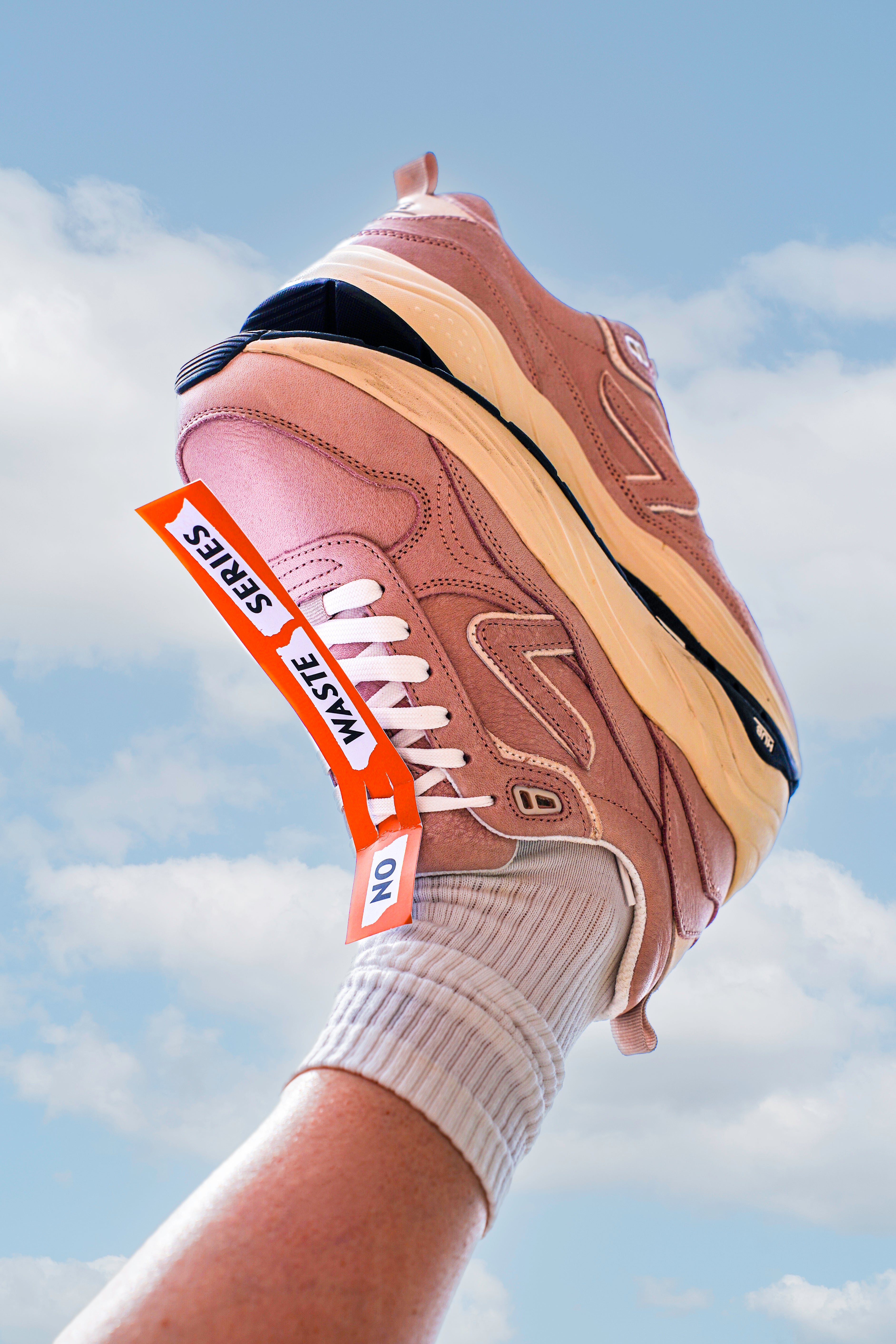 leg in the air holding another shoe, with the no waste label on the laces