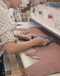 Female stamping pastel pink leather into shapes